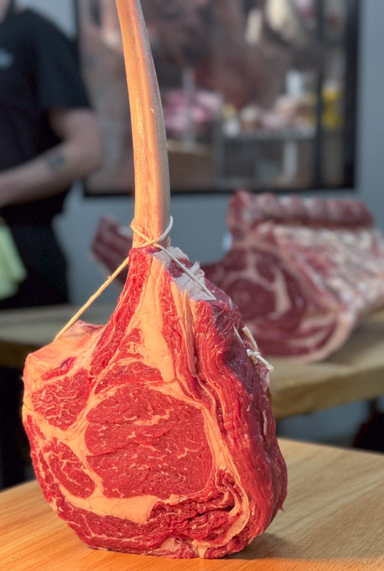 Thick-cut Tomahawk Steak with a dramatic bone-in presentation, crafted from premium AAA beef at ForeQuarter Butcher Shop in Kitchener