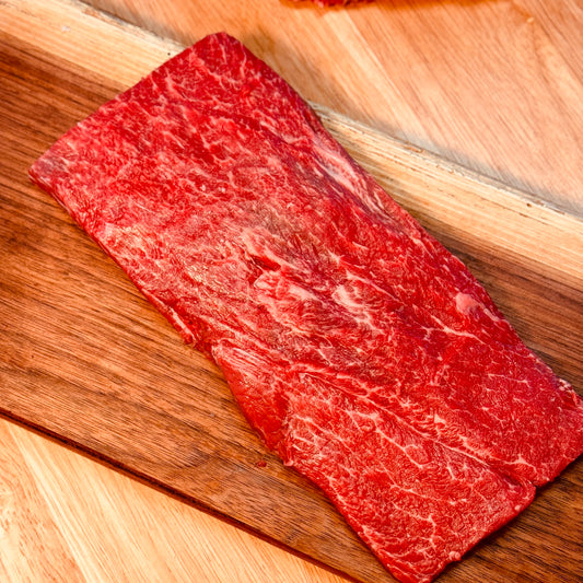 Flat Iron Steak on a butcher block in a butcher shop