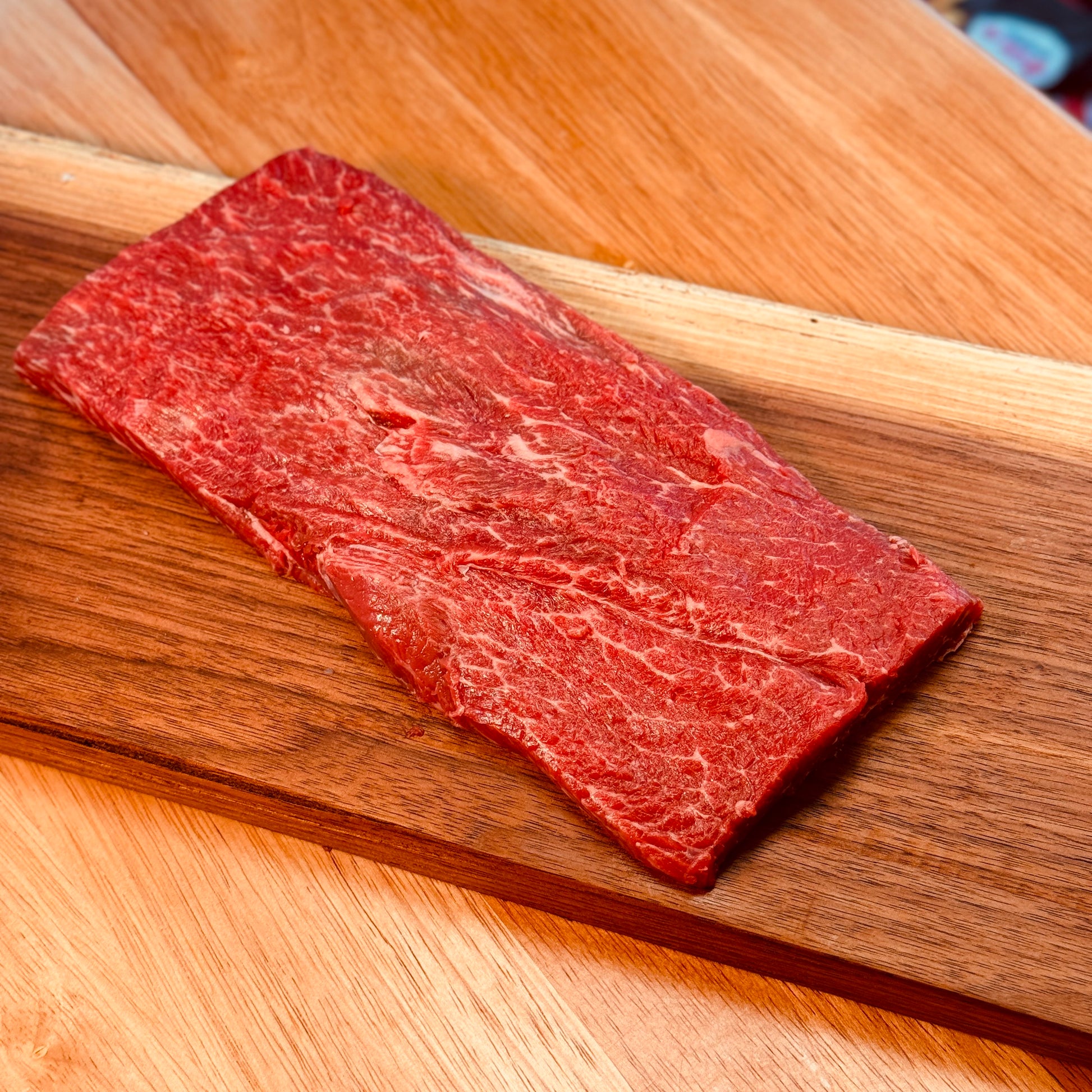 Flat Iron Steak on a butcher block in a butcher shop